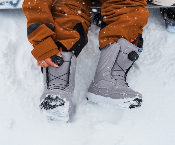 Snowboards Boots werden im Schnee eingestellt