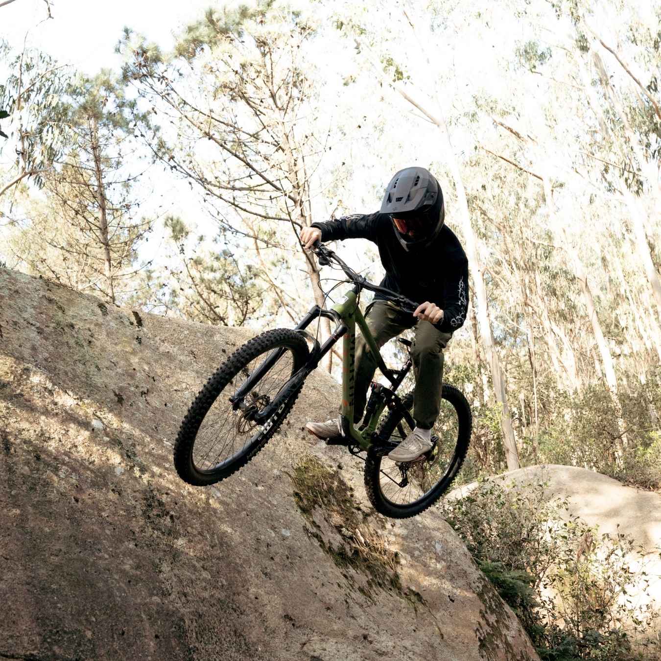 Person mit Downhill-Helm fährt an Felskante