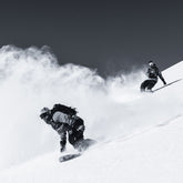 zwei Personen auf Snowboards