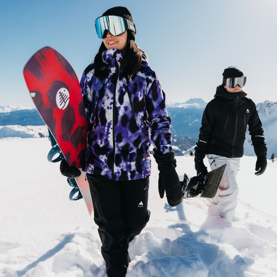 zwei Personen mit Snowboards in der Hand