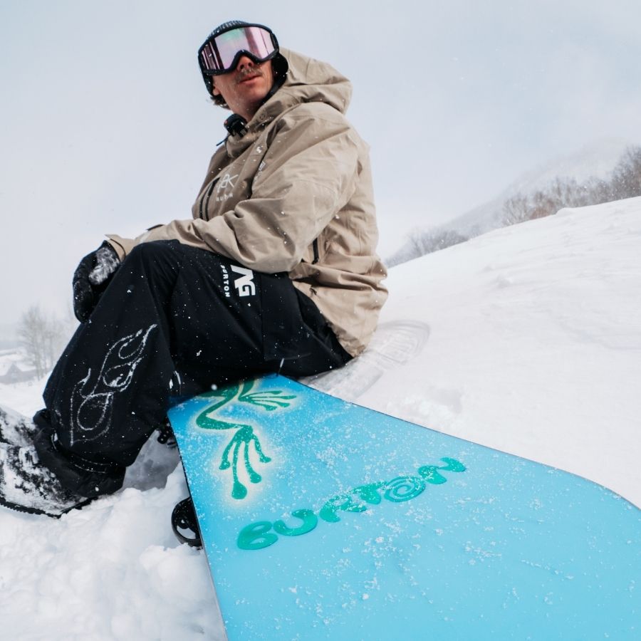 Mann sitzt auf Snowboard