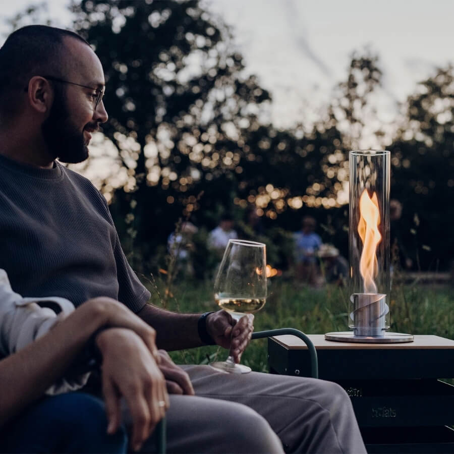 Mann mit Wein neben Tischfeuer