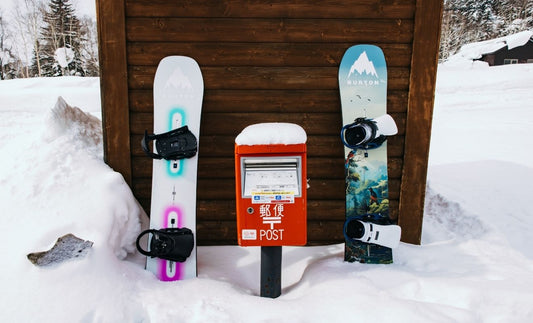 Snowboards unterschiedlicher Arten nebeneinander vor Hütte