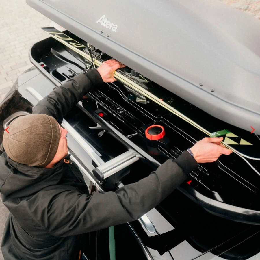 Person packt Equipment in Dachbox