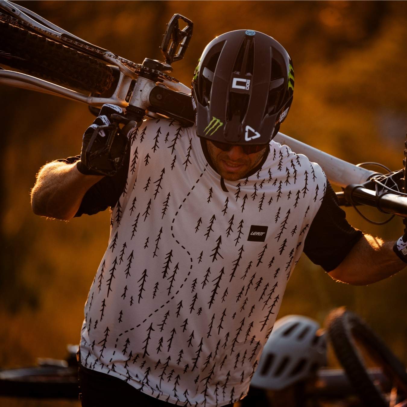 Mann mit Fahrradtrikot trägt Fahrrad