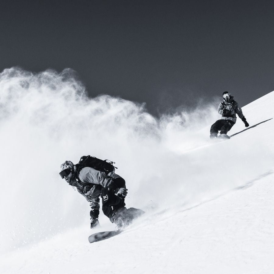 zwei Personen auf Snowboards